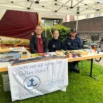 Bild vom Stand der SeglerInnen beim Gemeindefest mit Segelboot im Hintergrund.